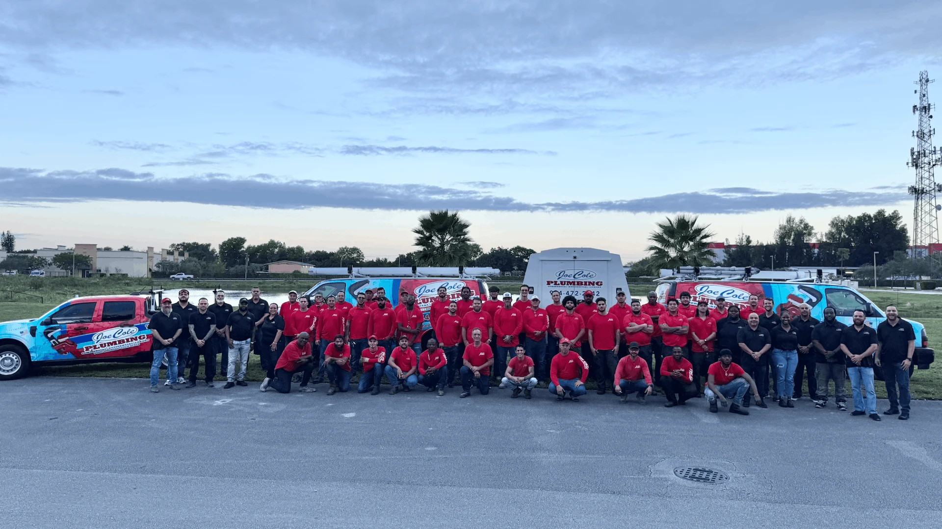 Joe Cole Plumbing team standing with company service trucks